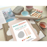 Petite Artisan Kids Clay Kit with clay, tools, and a magazine on a table.