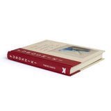 The book 'Furoshiki: And the Japanese Art of Gift Wrapping' by Tomoko Kanata, featuring a cream-colored cover with a vertical dark red spine and an illustration of a blue and white fabric gift wrap.