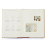 An open book showing a step-by-step guide with line drawings and small inset photos, likely explaining how to tie a bow. The pages are cream-colored with a dark red ribbon binding visible at the top and bottom.