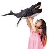 Child holding a large plush whale toy against a white background