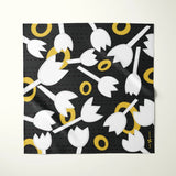 A square scarf with a black background and a repeating pattern of white tulips and yellow rings, displayed flat against a light off-white background.