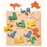 A wooden animal puzzle board with colorful animal pieces and cutout animal shapes, photographed on a plain light background.