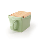 A square ceramic salt box in sage green with a hinged wooden lid, shown on a clean white background.