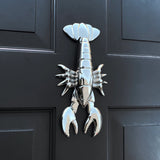 Metallic lobster door knocker on a black door