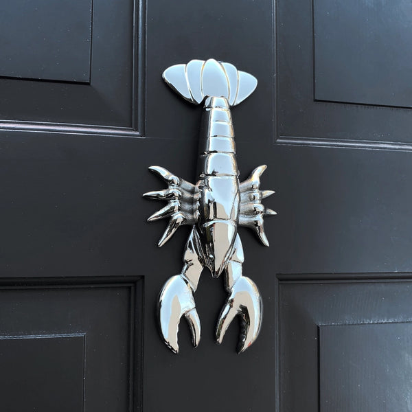Metallic lobster door knocker on a black door