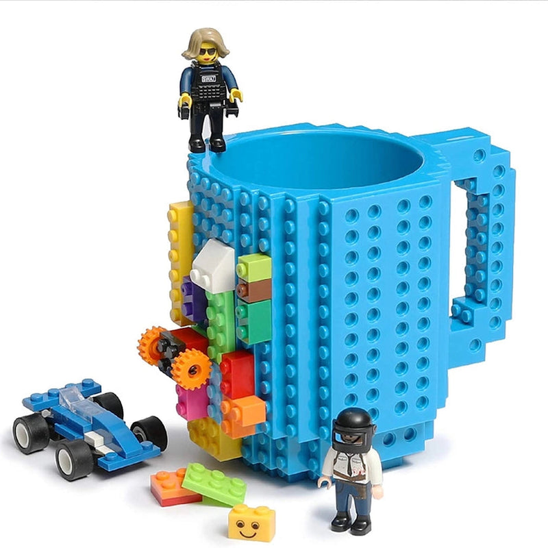 Blue mug with building block design, colorful blocks, and small figures on a white background