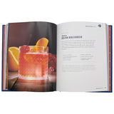 Open book showing a cocktail recipe with a glass of red cocktail and garnishes.