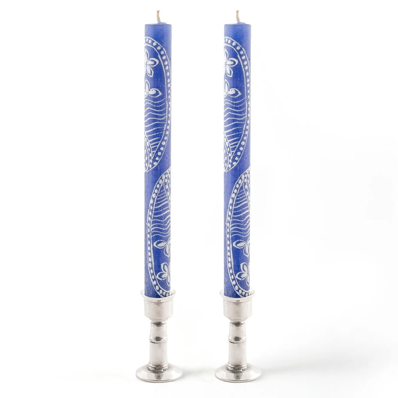 Two blue candles with silver bases on a white background