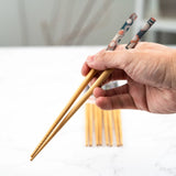 Hand holding wooden chopsticks with a blurred background