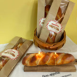 Loaves of bread shaped candles in brown paper bags with a basket on a yellow background