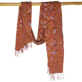 Patterned scarf with fringes hanging on a wooden rod against a white background
