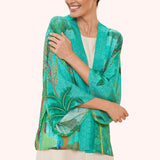 Woman wearing a turquoise floral kimono-style garment on a white background