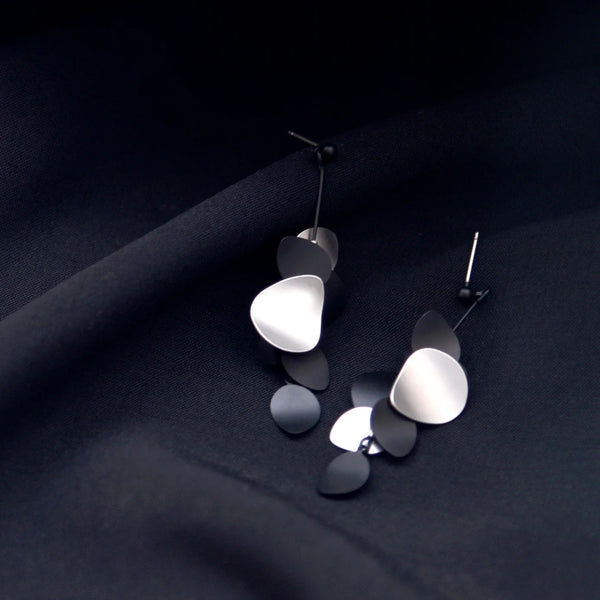 Pair of modern earrings on a dark fabric background