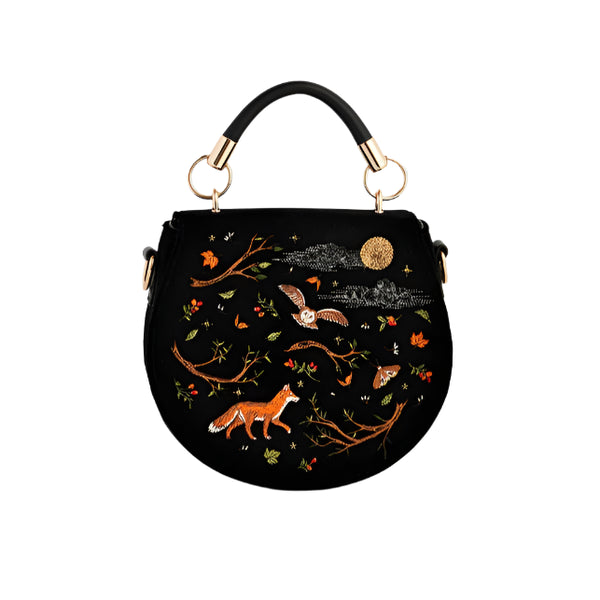 Black handbag with nature-themed embroidery on a light gray background