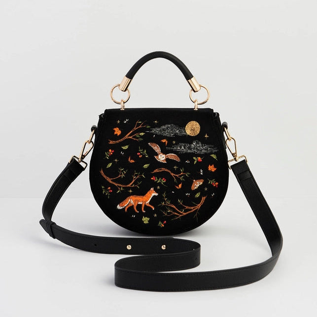 Black handbag with embroidered designs on a light gray background