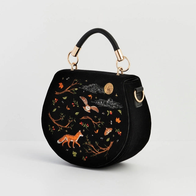 Black handbag with nature-themed embroidery on a light gray background