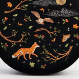 Embroidered design of a fox, owl, and branches on a black background