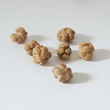 Several small, textured, tan-brown candies scattered on a plain white surface.