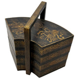Decorative black and gold tiered box with handle on a white background