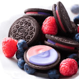 Oreo cookies, blueberries and raspberries in a pile on a white background