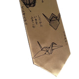 A gold necktie featuring black line drawings of origami cranes and Japanese text, shown against a plain white background.