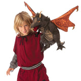 Child in a red costume holding a toy dragon with orange wings and black body.