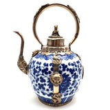 Decorative teapot with blue floral patterns and silver accents on a white background