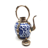 Decorative teapot with blue floral patterns and silver accents on a white background